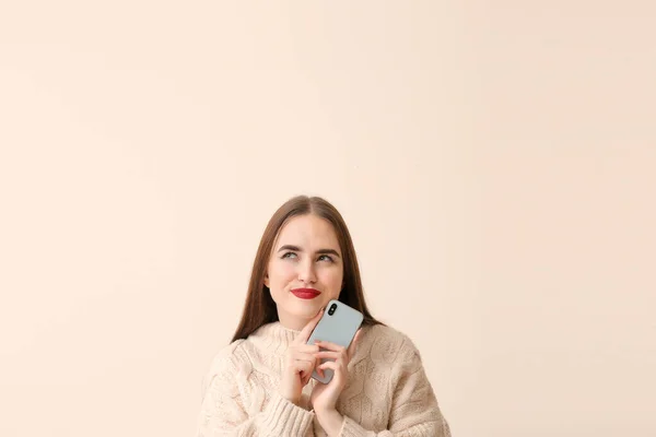 Schöne junge Frau mit Handy auf hellem Hintergrund — Stockfoto