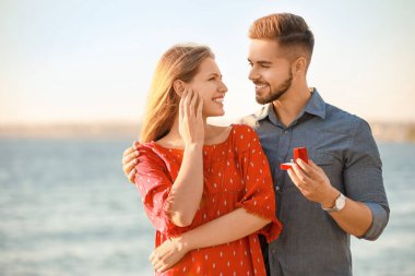 Genç adam nehir kenarındaki sevgilisine evlenme teklif ediyor.