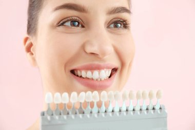 Arka planda diş rengi örnekleri olan güzel genç bir kadın.