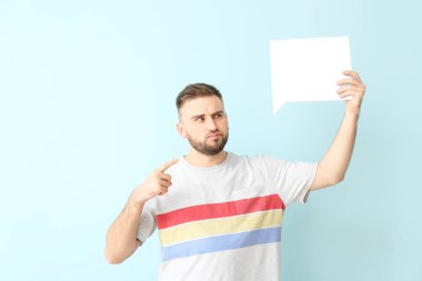 Renk arkaplanında boş konuşma balonu olan kafası karışmış genç bir adam.