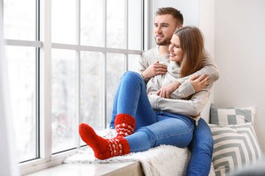 Mutlu çift evde pencere yakınında istirahat