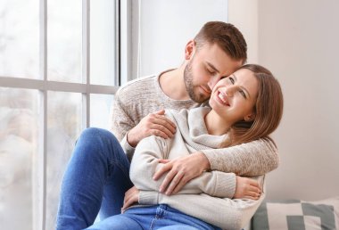 Mutlu çift evde pencere yakınında istirahat