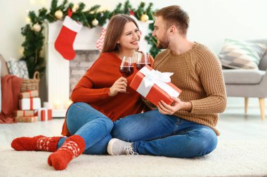 Noel arifesinde evde bir kadeh şarap ve hediyeyle mutlu bir çift.