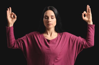 Karanlık arka planda meditasyon yapan kadın.