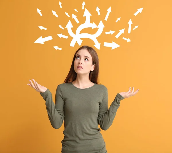 Bedachtzame jonge vrouw en pijlen op kleur achtergrond. Begrip "keuze" — Stockfoto