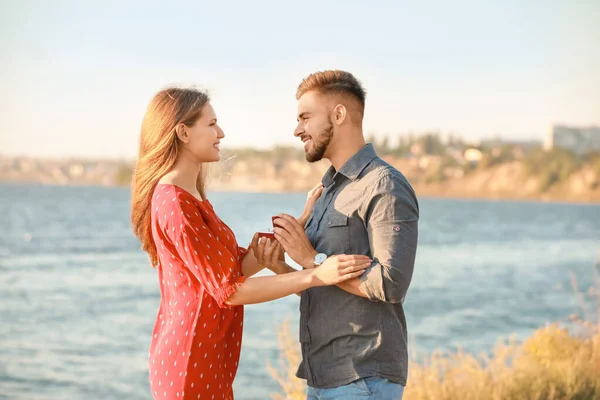 Young man proposing to his beloved near river — Stock Photo, Image