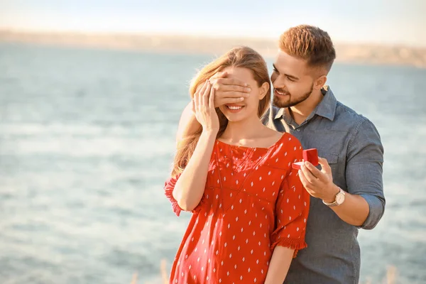 Genç adam nehir kenarındaki sevgilisine evlenme teklif ediyor. — Stok fotoğraf