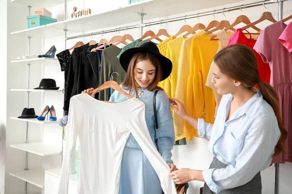 Vendeur aider la jeune femme à choisir des vêtements dans le magasin — Photo