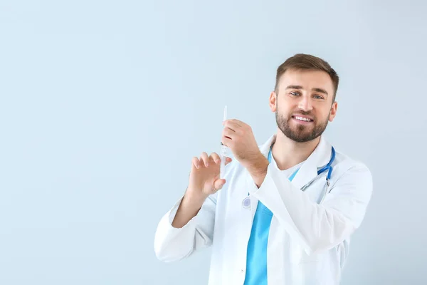 Portrait of male doctor with syringe on light background — 스톡 사진