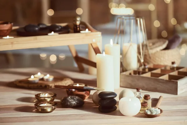 Velas brillantes con suministros de spa en la mesa —  Fotos de Stock