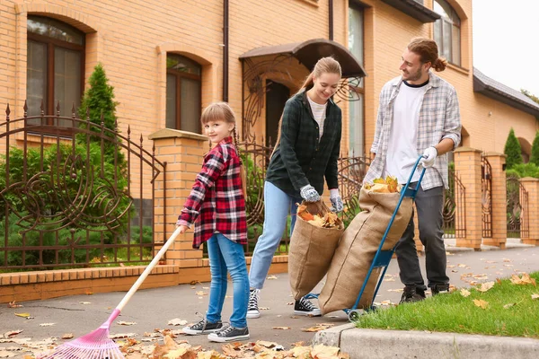 Family cleaning up autumn leaves outdoors — Stock Photo, Image