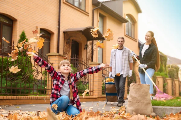 Família limpando folhas de outono ao ar livre — Fotografia de Stock