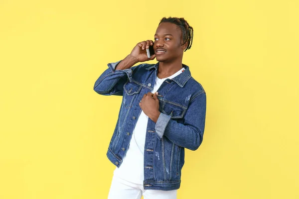 Portrait of stylish African-American man talking by mobile phone on color background — Stock Photo, Image
