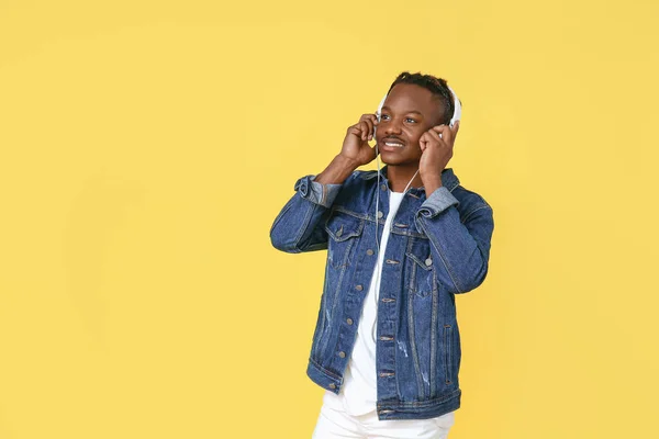 Portrait of stylish African-American man listening to music on color background — Stock Photo, Image