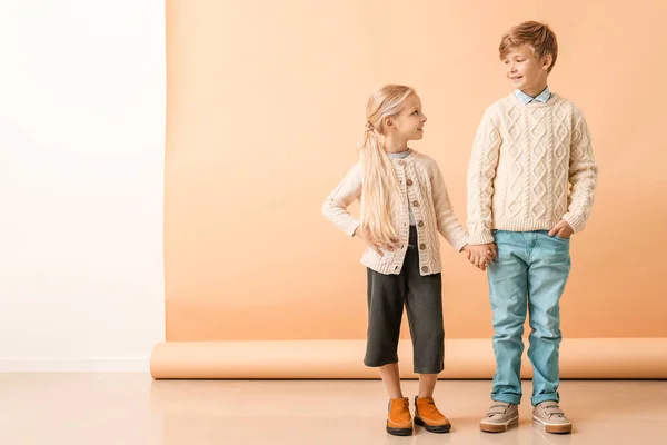 Bambini piccoli e carini in abiti autunnali vicino alla parete di colore — Foto Stock