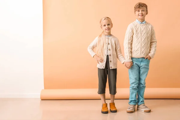 Bambini piccoli e carini in abiti autunnali vicino alla parete di colore — Foto Stock