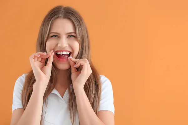 Beautiful young woman with dental floss on color background — Stock Photo, Image