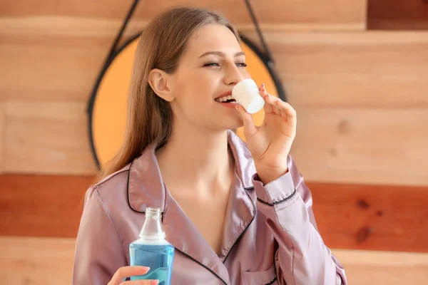 Beautiful young woman with mouth rinse in bathroom — Stock Photo, Image