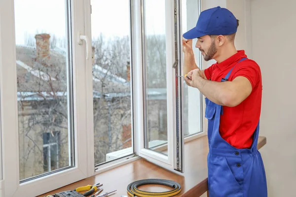 Молодой рабочий устанавливает окно в квартире — стоковое фото