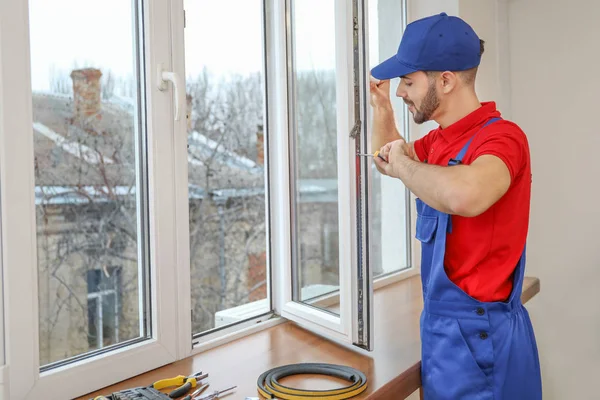 Jovem trabalhador instalando janela em plano — Fotografia de Stock