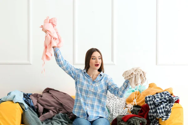 Vervloekte vrouw met hoop kleren op de bank binnen — Stockfoto