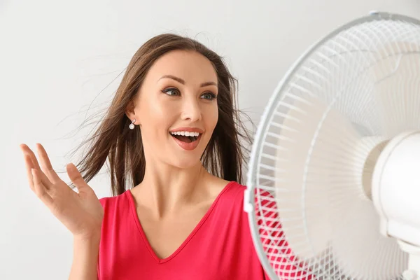 Mulher feliz com ventilador elétrico no fundo branco — Fotografia de Stock