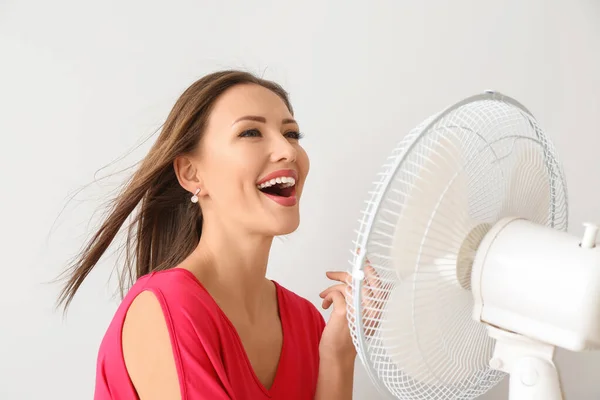 Mujer feliz con ventilador eléctrico sobre fondo blanco —  Fotos de Stock