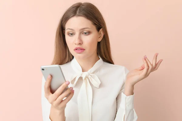 Traurige Geschäftsfrau mit Handy auf farbigem Hintergrund — Stockfoto