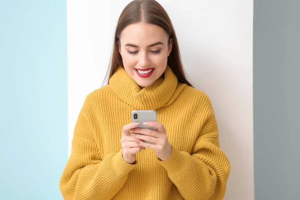 Beautiful young woman with mobile phone on light background — Stock Photo, Image