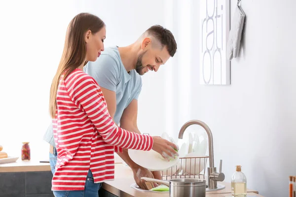 Casal feliz lavar pratos na cozinha — Fotografia de Stock