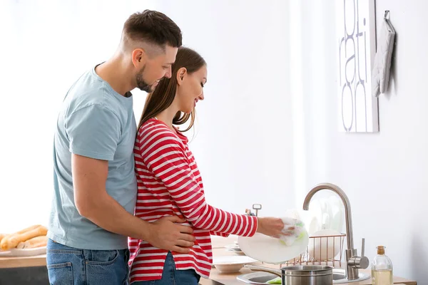 Pareja feliz lavando platos en la cocina — Foto de Stock