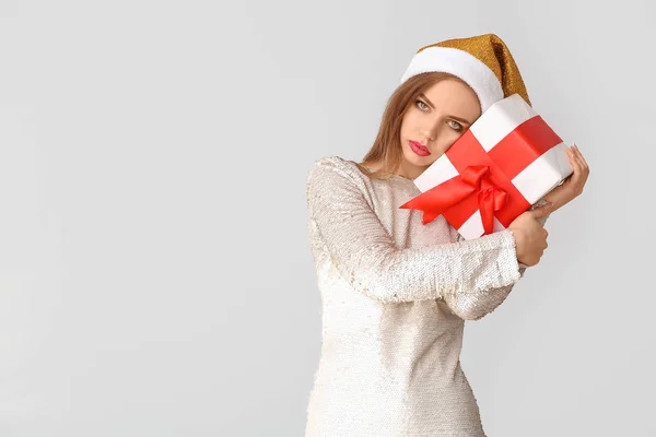 Donna ubriaca con cappello Babbo Natale e regalo su sfondo chiaro — Foto Stock