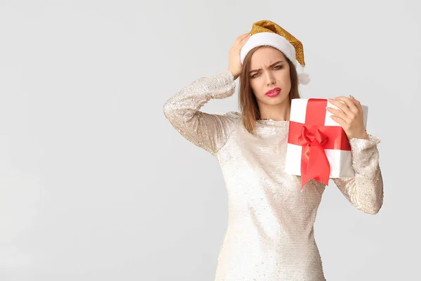 П'яна жінка з капелюхом Санта Клауса і подарунком на світлому тлі — стокове фото