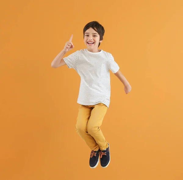 Saltando menino com dedo indicador levantado no fundo de cor — Fotografia de Stock
