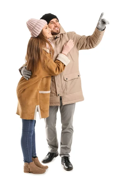 Portrait of happy couple in winter clothes showing something on white background — Stock Photo, Image