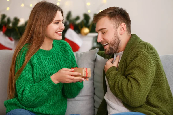 Happy woman giving present to her boyfriend at home on Christmas eve — Stock Photo, Image