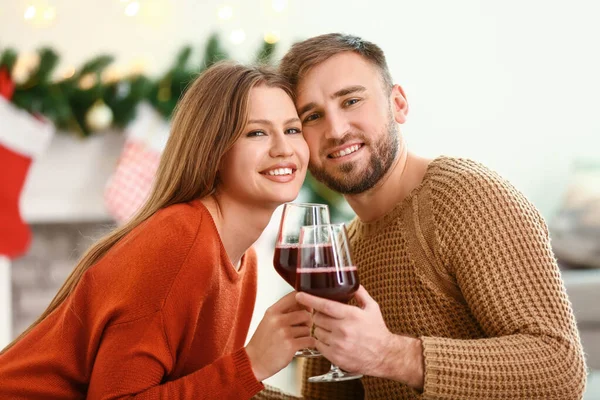 Счастливая молодая пара с бокалами вина отдыхает дома в канун Рождества — стоковое фото