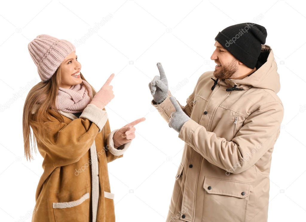 Portrait of happy couple in winter clothes showing something on white background