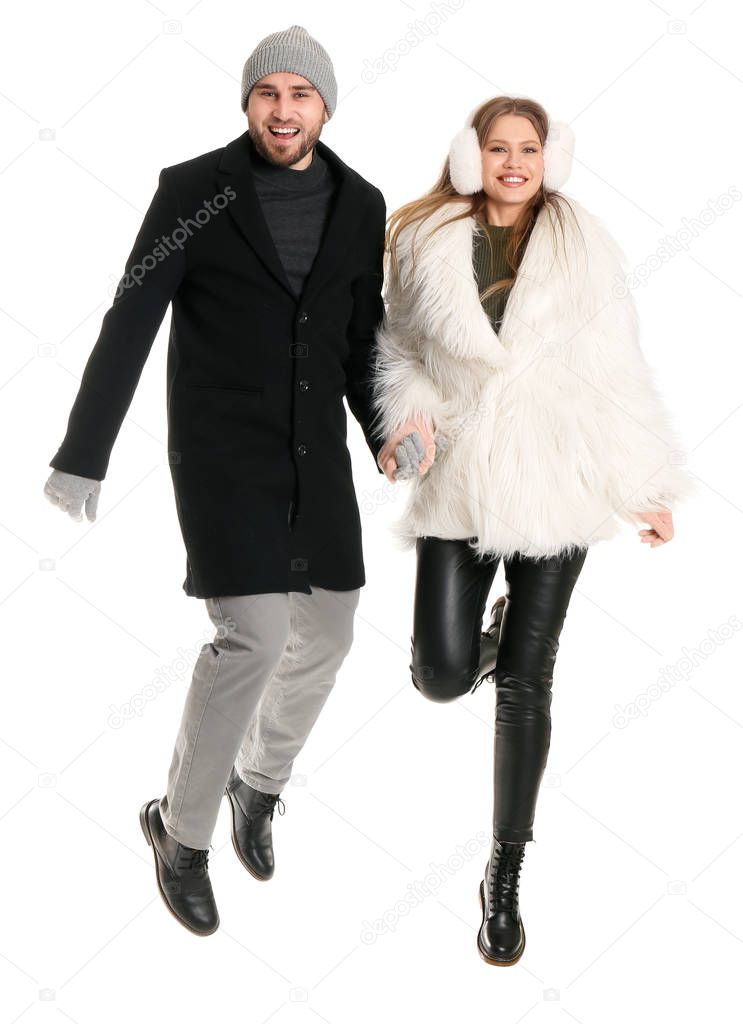 Portrait of jumping couple in winter clothes on white background