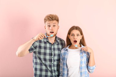 Renkli arka planda dişlerini fırçalayan genç çift şok oldu.