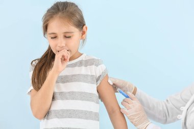 Doktor, küçük kızı ışığa karşı aşılıyor.