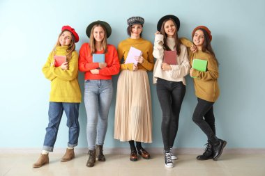 Renk duvarının yanında kitapları olan genç kadınlar