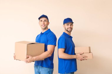 Delivery men with boxes on color background