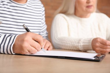 Mature man signing a sale and purchase contract in his new house, closeup