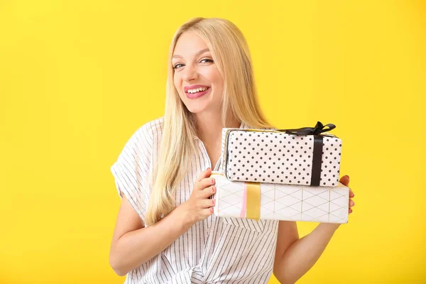 Beautiful young woman with gifts on color background — Stock Photo, Image