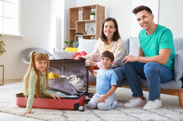 Счастливая семья веселится, собирая чемоданы дома — стоковое фото