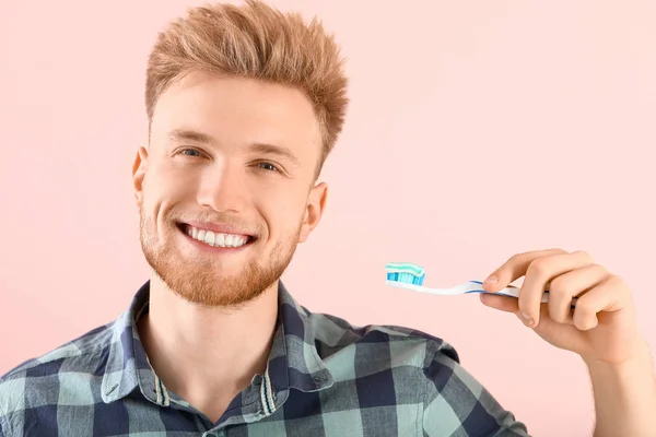 Young man brushing teeth on color background — Stock Photo, Image