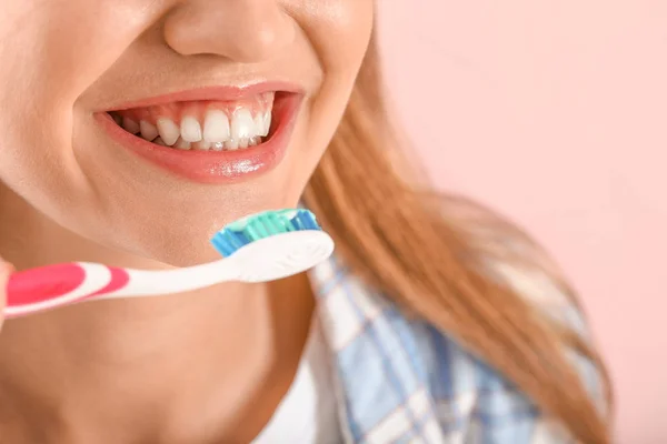 Mladá žena čištění zubů na barevném pozadí, detailní záběr — Stock fotografie