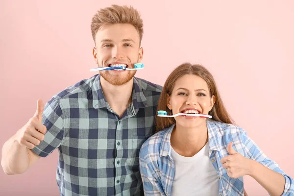Mladý pár se zubními kartáčky na barevném pozadí — Stock fotografie
