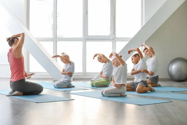 Niños pequeños practicando yoga con instructor en gimnasio — Foto de Stock